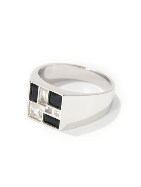 A silver signet ring featuring a geometric face with alternating black and clear square gemstones, set against a plain white background.