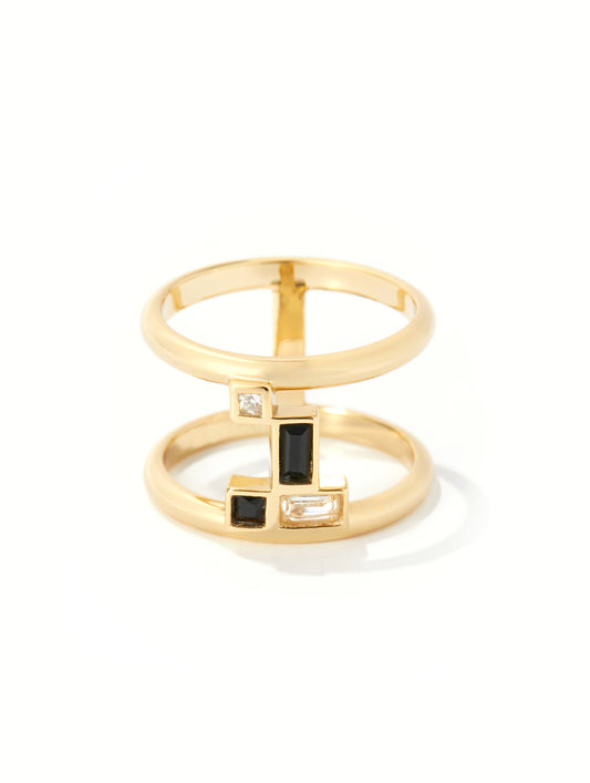 A gold geometric ring with stacked bands and rectangular black and clear gemstone accents, photographed on a clean white background.