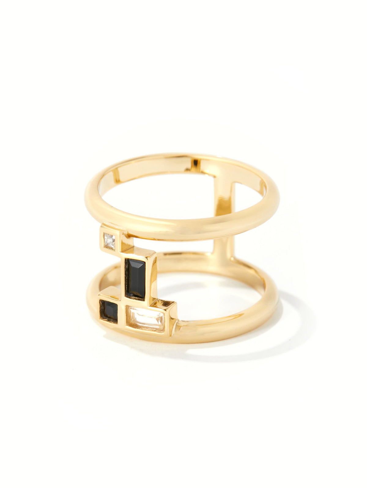 A gold geometric ring featuring a multi-band open design with rectangular bezel-set black and clear stones, shown on a clean white background.