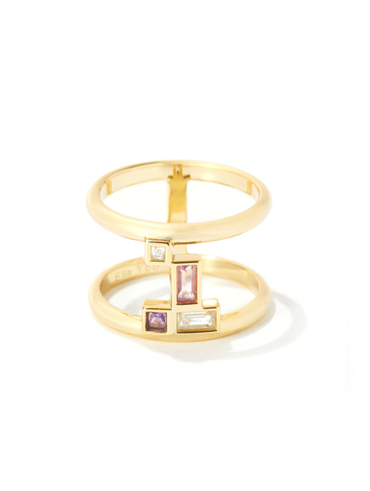 A gold geometric ring with stacked bands and rectangular pink and clear gemstones, photographed on a clean white background.