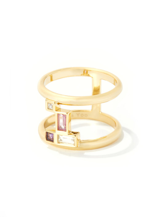 A gold open-band ring with geometric settings featuring clear baguette and round stones, plus pink rectangular stones, photographed on a clean white background.