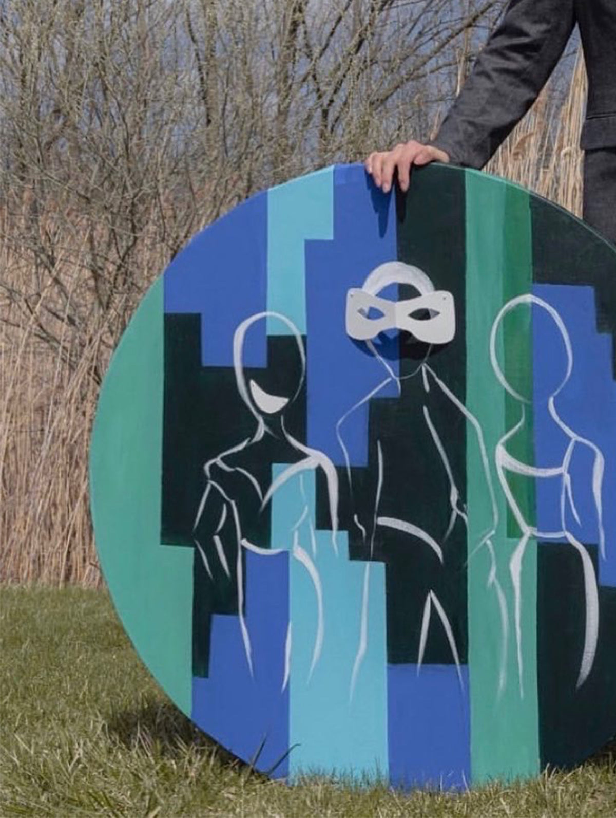 Contemporary circular painting with geometric blue and green forms and abstract human figures, photographed outdoors.