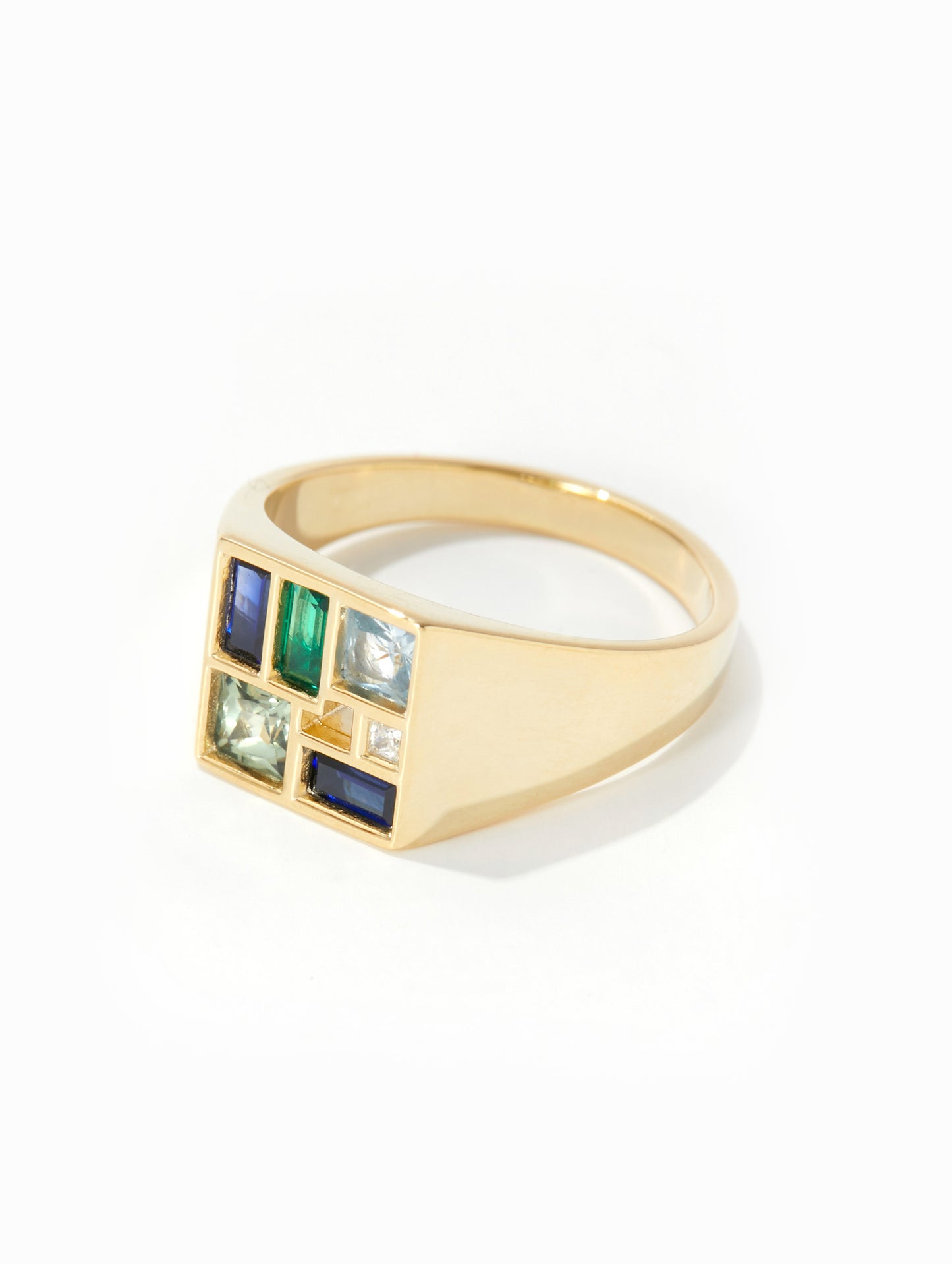 A gold signet ring featuring a square face with six colorful inset stones in blue, green, and clear crystal settings, photographed on a clean white background.