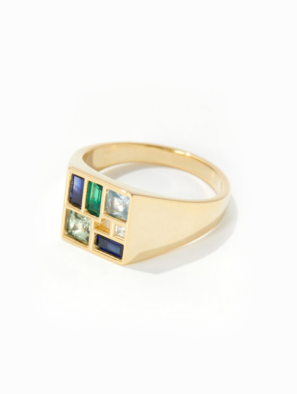 A gold signet ring featuring a square face with six colorful inset stones in blue, green, and clear crystal settings, photographed on a clean white background.