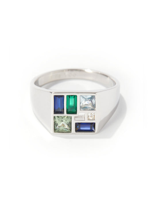 A silver signet ring featuring a grid of colorful gemstones, including blue, green, and clear stones, set against a plain white background.