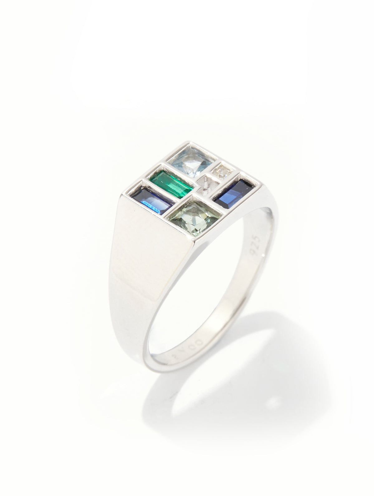A silver signet ring featuring a square face set with baguette-cut colored gemstones in green, blue, and white, alongside a small clear stone, photographed on a clean white background with a soft shadow.