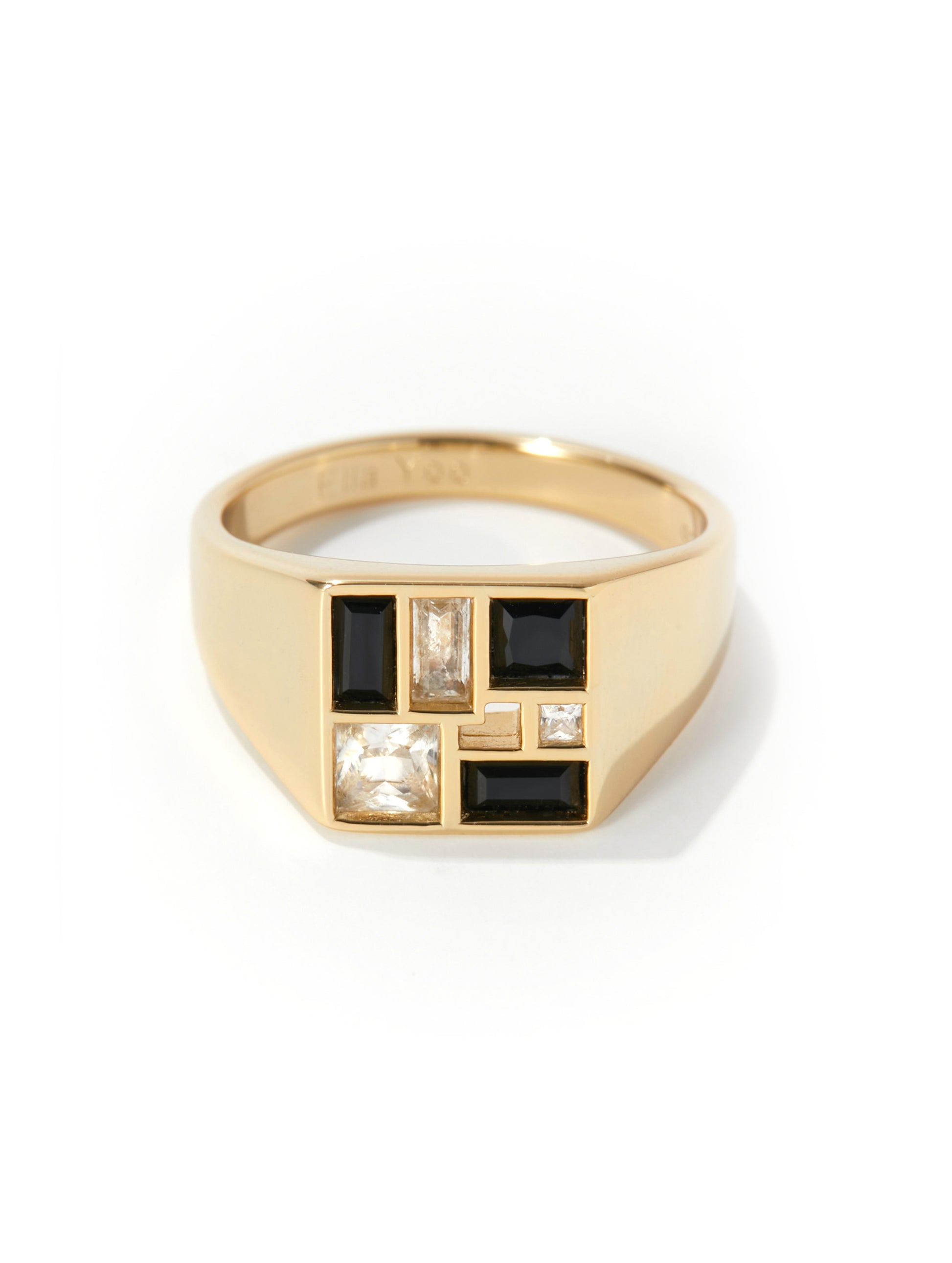 A gold signet ring featuring a geometric face with black baguette and round stones, set against a clean white background.