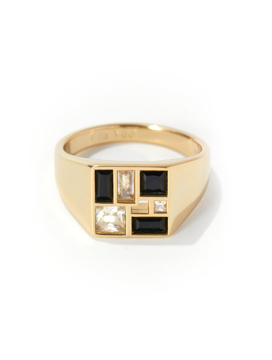 A gold signet ring featuring a geometric face with black baguette and round stones, set against a clean white background.