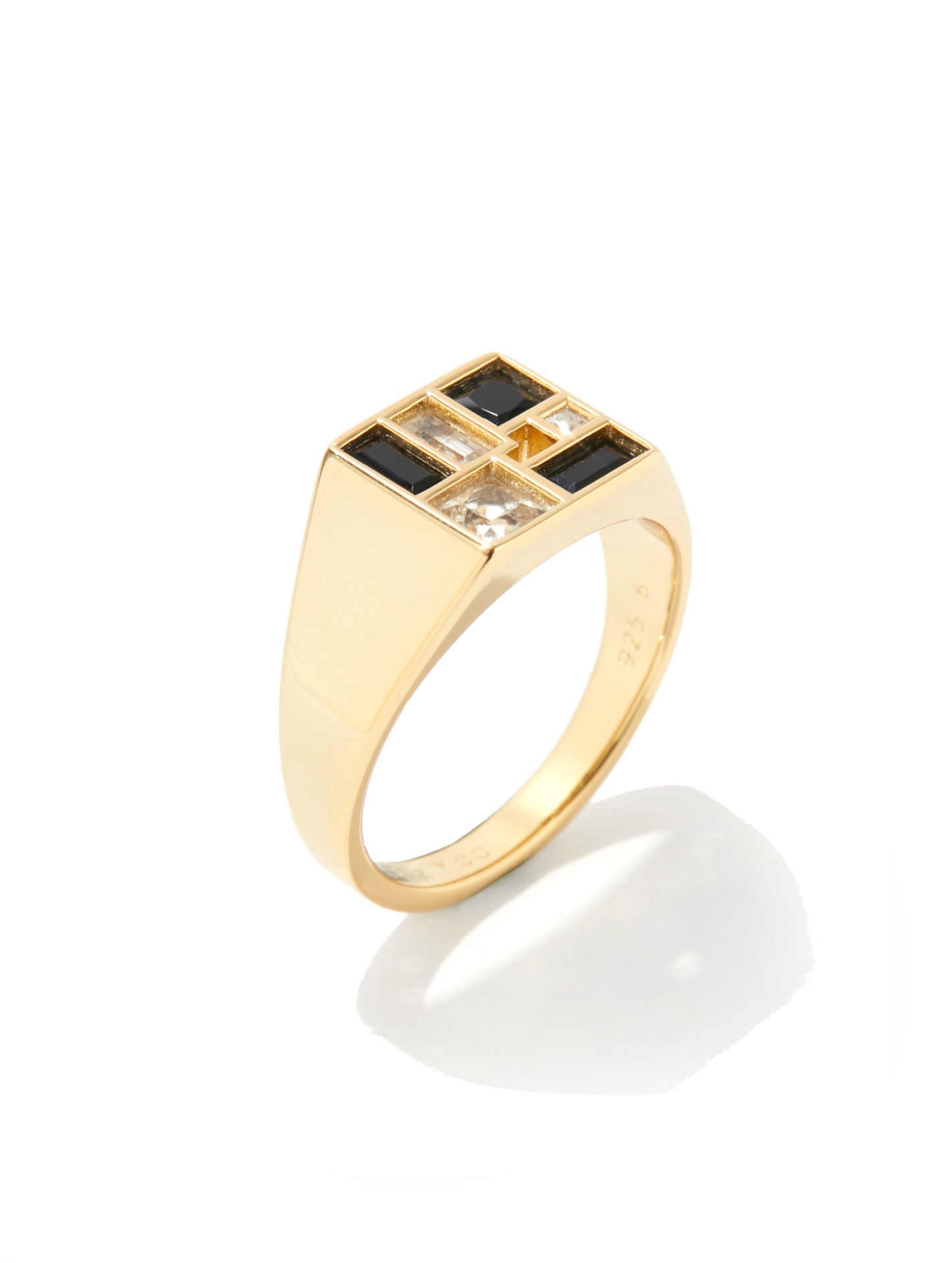 A gold signet ring featuring a square top set with alternating black and clear baguette-cut stones, shown on a clean white background with a soft reflection.