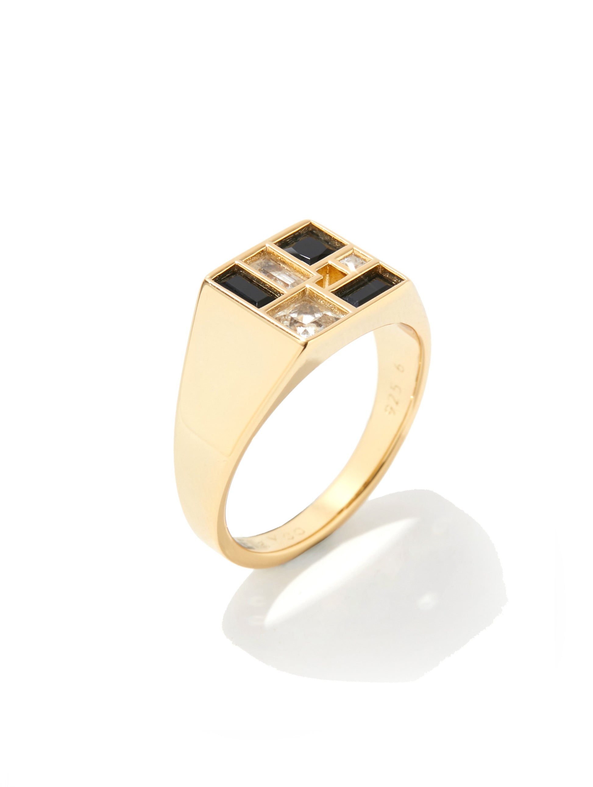 A gold signet ring featuring a square top set with alternating black and clear baguette-cut stones, shown on a clean white background with a soft reflection.