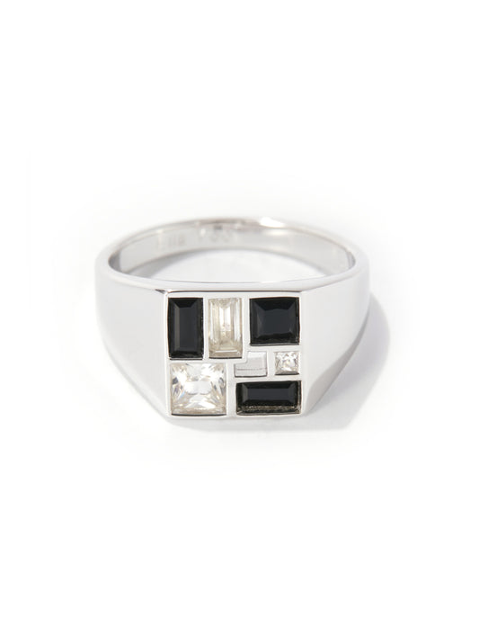 A silver signet ring featuring a geometric face with black rectangular stones, a clear baguette-cut stone, and a clear square-cut stone, set against a plain white background.