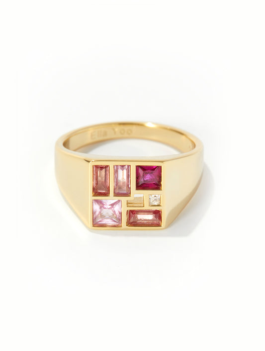 A gold signet ring featuring a geometric face set with pink and magenta baguette and princess-cut gemstones, and a small clear accent stone, shown on a white background.