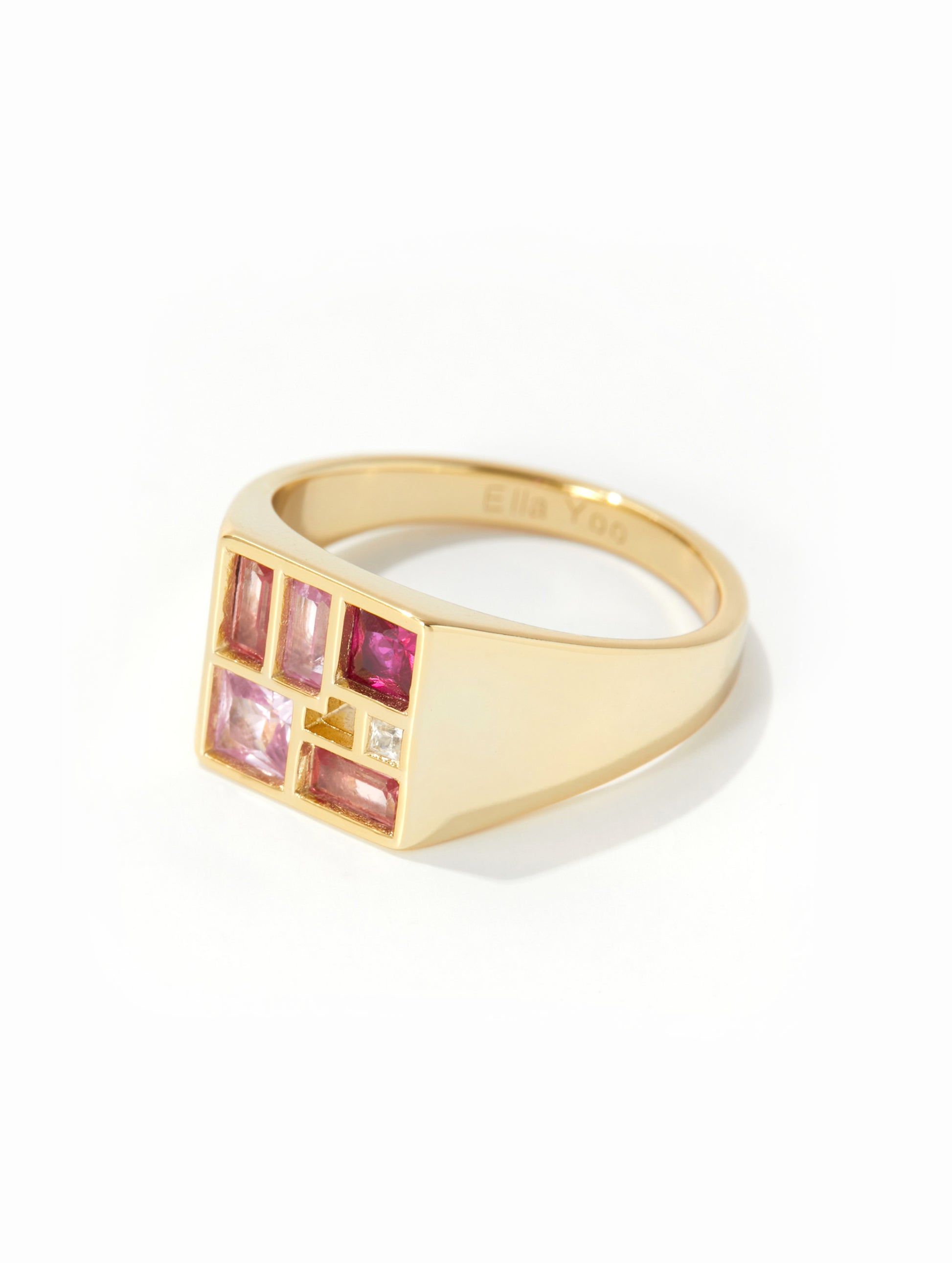 A gold signet ring featuring a grid of pink and clear gemstones on the face, photographed on a clean white background.