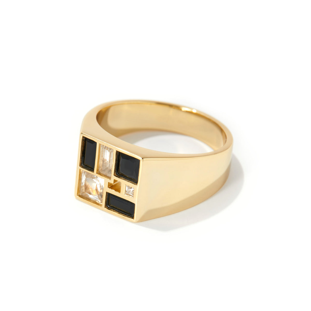 A gold signet ring with a geometric face featuring black square inlays and clear rectangular stones, set against a plain white background.