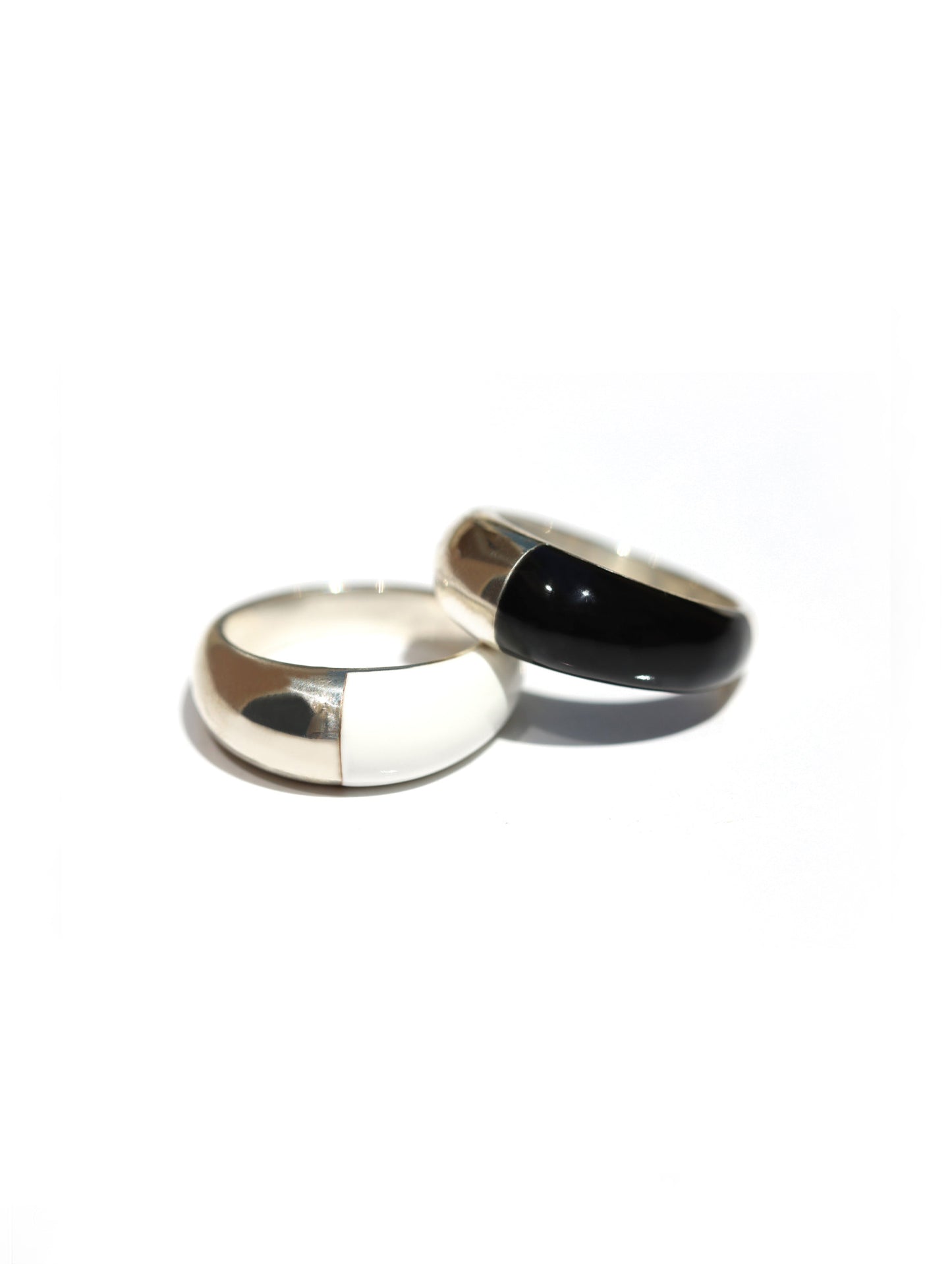 Two minimalist metal rings on a white background, one polished silver-toned and the other polished black.