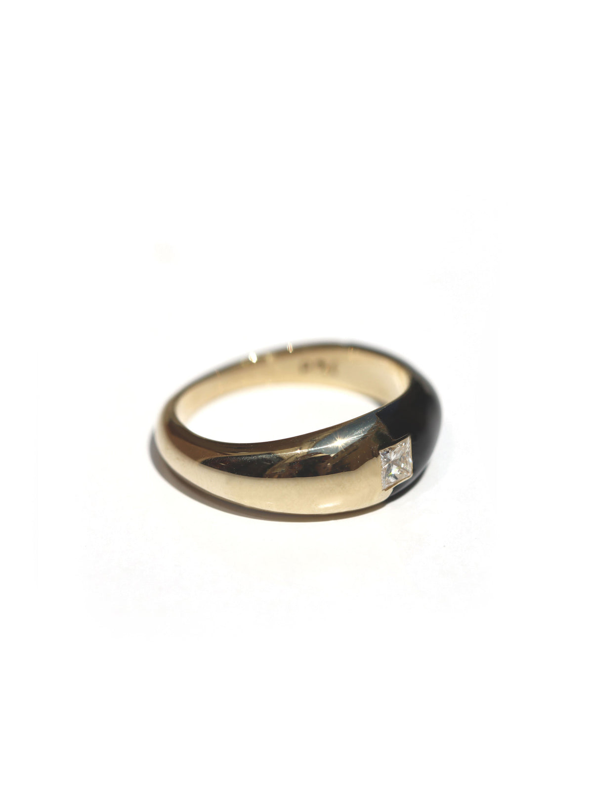 A yellow gold ring with a small square-cut clear gemstone, photographed on a plain white background.