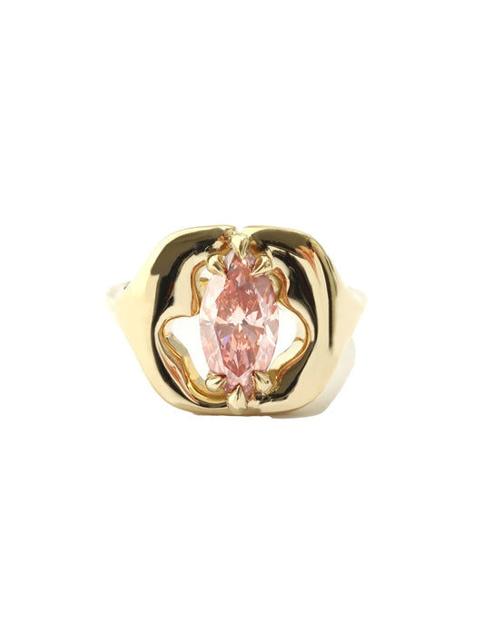 A gold ring featuring a central marquise-cut pink gemstone in a decorative openwork setting, shown against a plain white background.